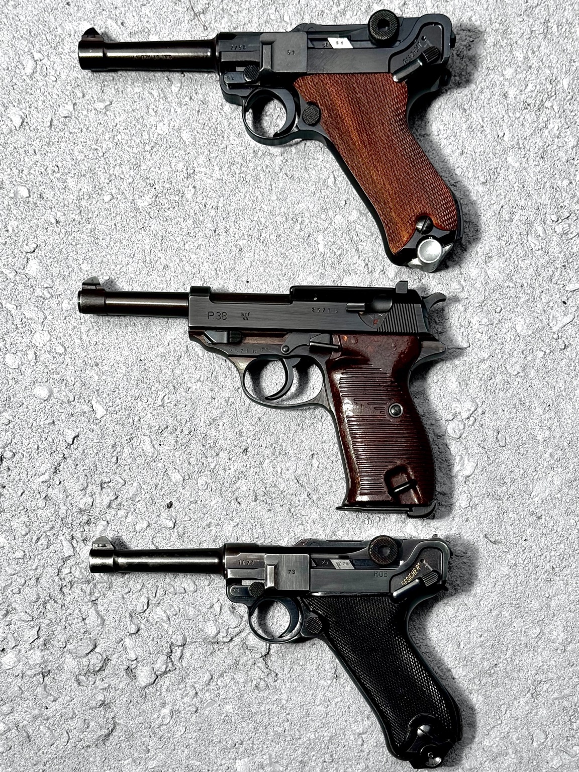Three German military pistols: a Mauser Luger, a wartime P38, and a Mauser Luger
